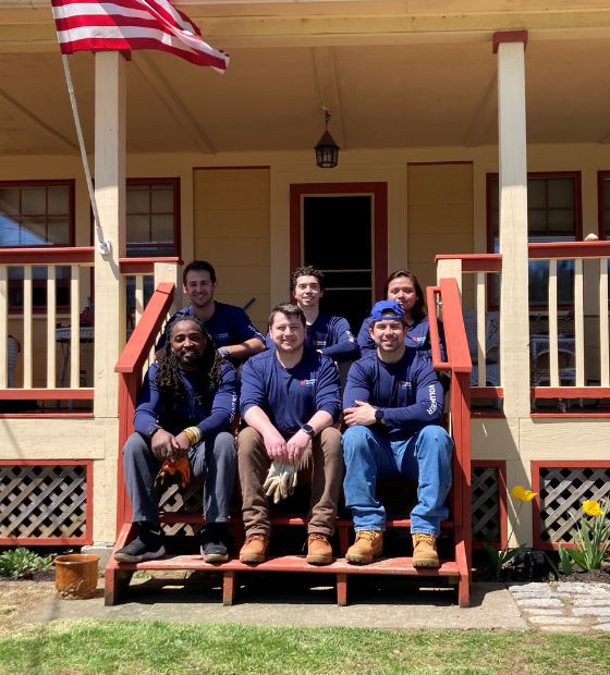 Group of NSB employees sitting on house doorstep