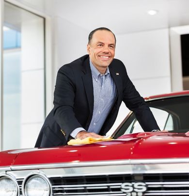 Man wiping down a vehicle in a car dealership