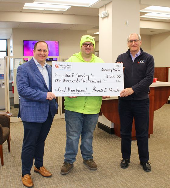 Winner holding big check with bank team