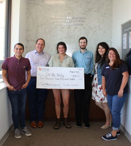Winner holding big check with bank team